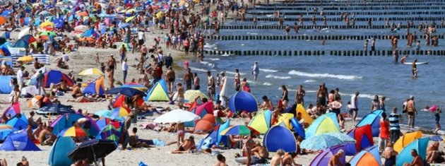 Urlauber am Strand von Warnemünde: Weiter fester Ferienbeginn in Bayern und Baden-Württemberg. Foto: © dpa.
