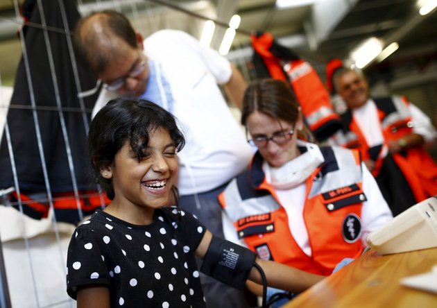 A Syrian refu­gee gets a medical check upon her arrival in Germany; Photo: Kai Pfaffenbach / Reuters